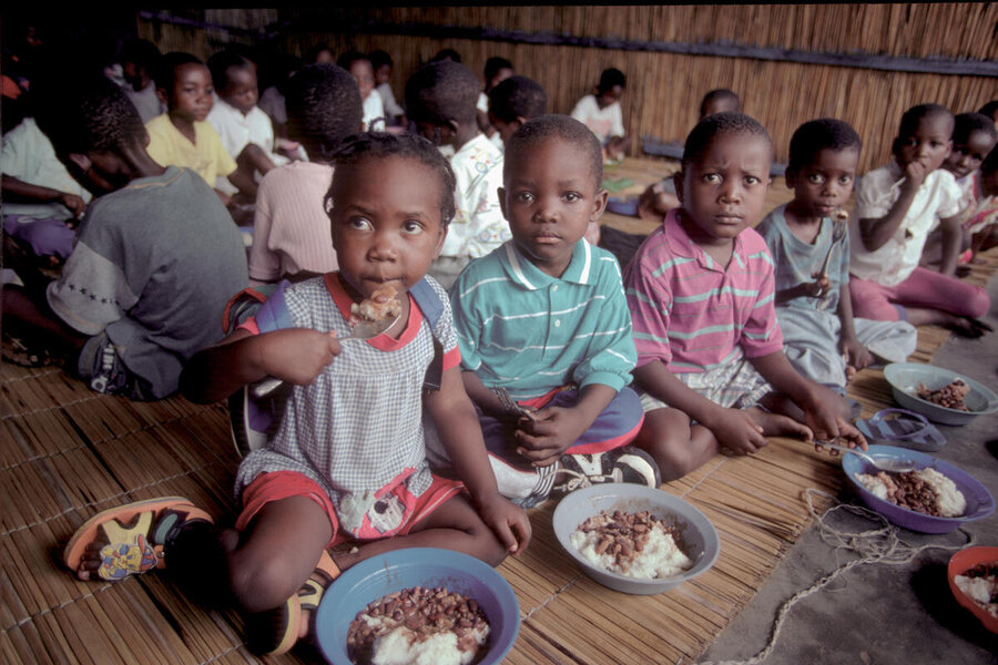 Young children at a school in Mozambique sat in rows on mats taking school meals in 199