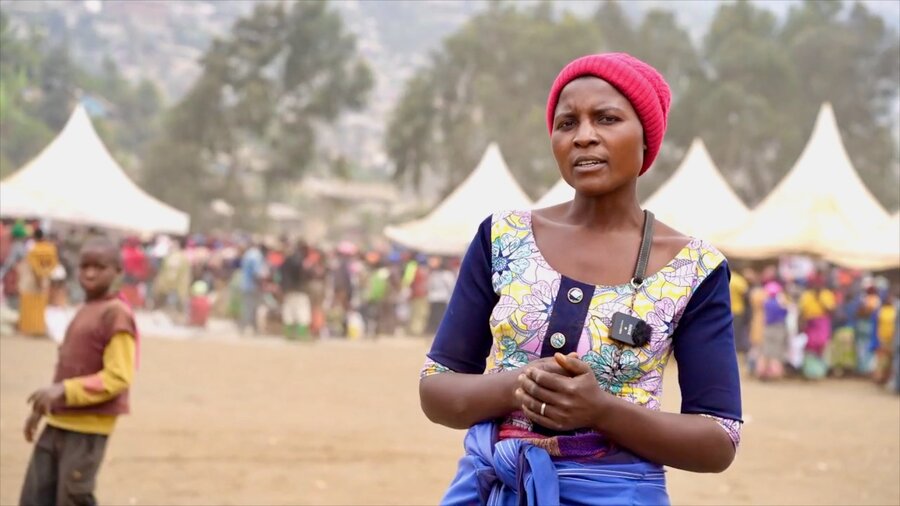 A woman sporting a colourful dress and red cap stands in front of a food distribution centre in eastern DRC. Photo: WFP/Benjamin Anguandia