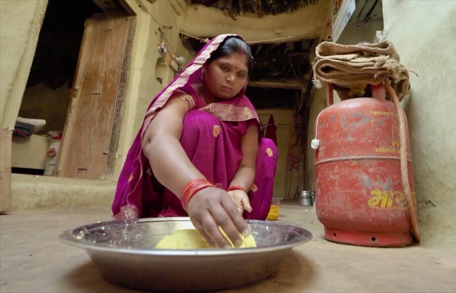 A woman in a pink sari rolls bolls of fortified rice dough for cooking. Photo: WFP