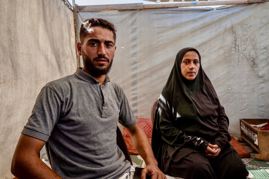 A man sporting a T-shirt and his wife, wearing a dark gown and headscarf, sit in a white tent. Photo: WFP/Maxime Le Lijour