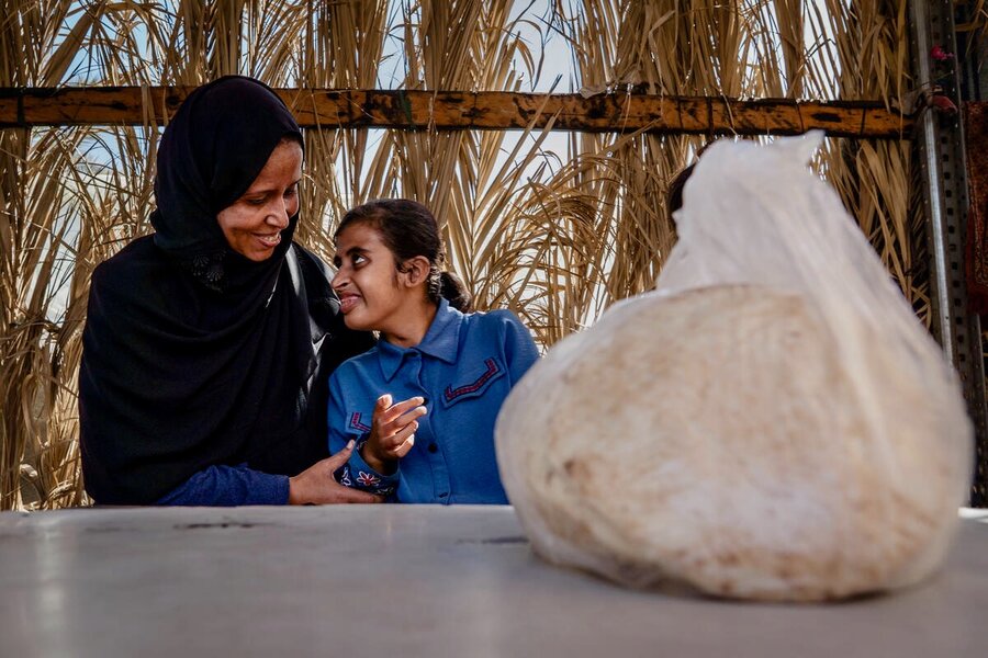 A smiling mother and daughter in the background, with a package of pita bread in the foreground. Photo: WFP/Maxime Le Lijour