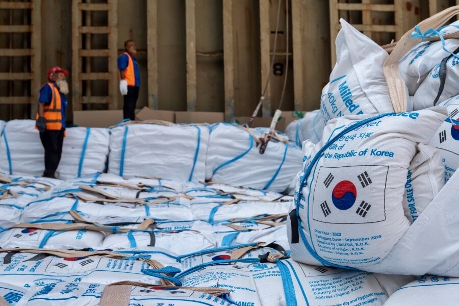 Port workers in background and white bags of Korean rice with the country's flag stamped on them arriving at Bangladesh's Chittagong Port. Photo: WFP/Rawful Alam