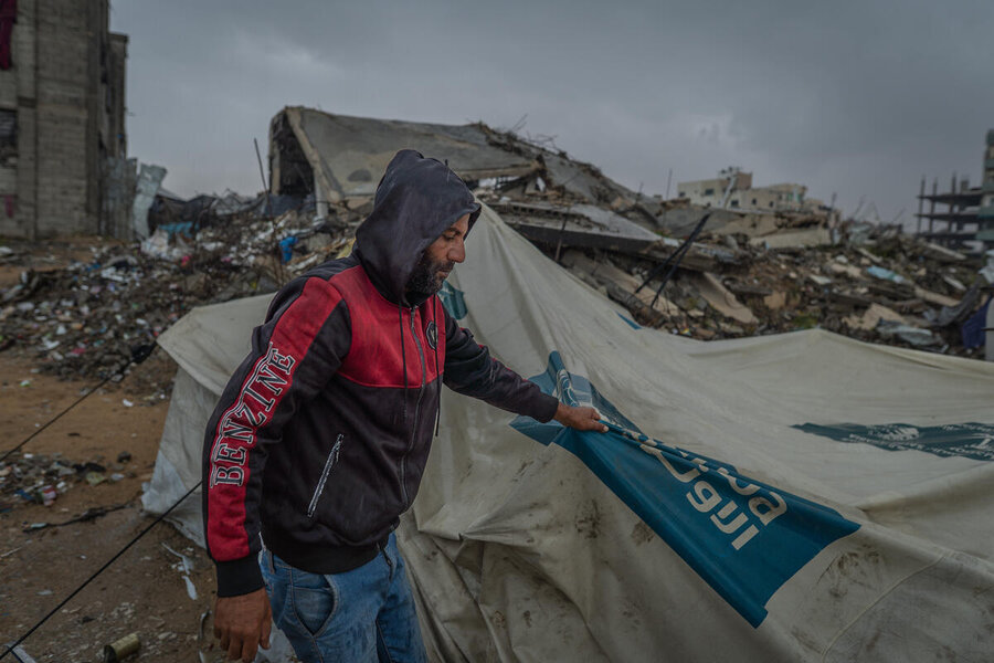 A man tugs at a tarpaulin tent in Gaza