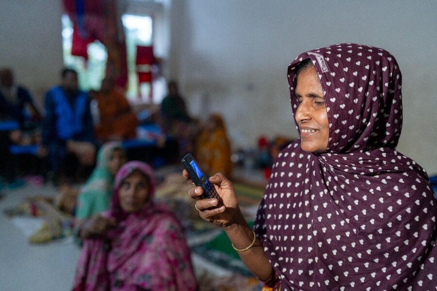 A Muslim elder smiles as she looks at her mobile phone