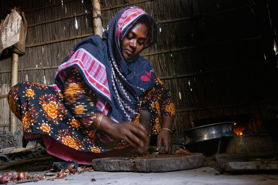 A woman wearing a colourful headscarf and gown prepares a meal in her small home. Photo: WFP/Samantha Reinders