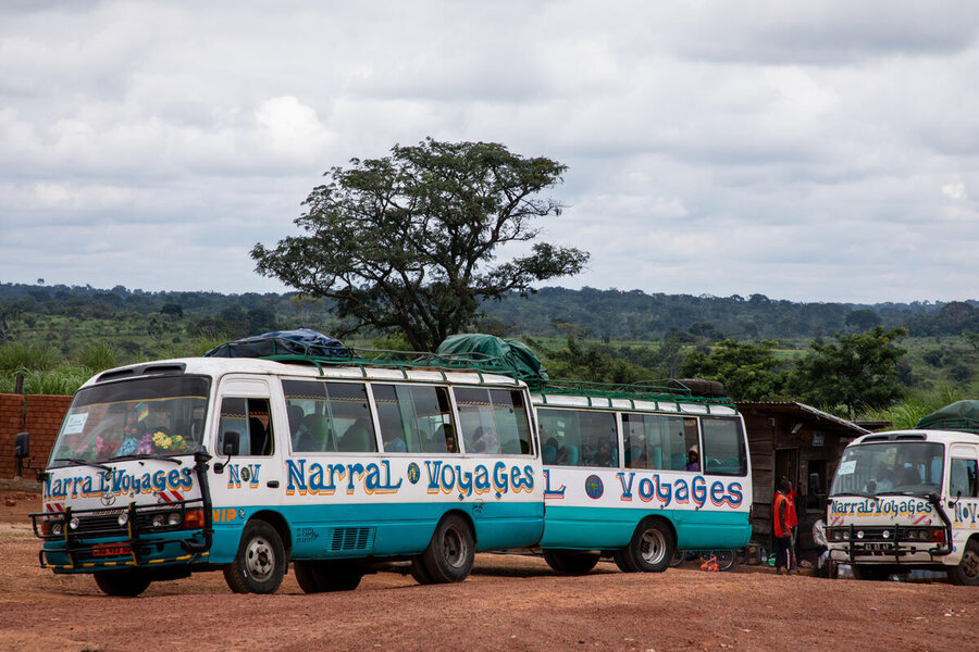 Blue-and-white minibuses on a red dirt road backdropped by trees. Photo: WFP/Aurore Vinot