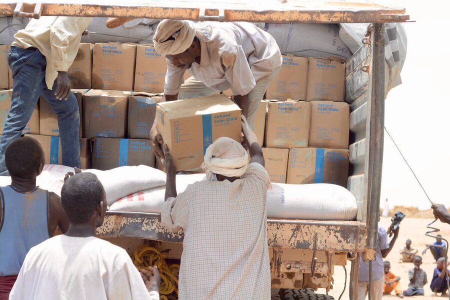 Men in white robes and turbans unload boxes of WFP food from a truck. Photo: WFP/Mohamed Galal