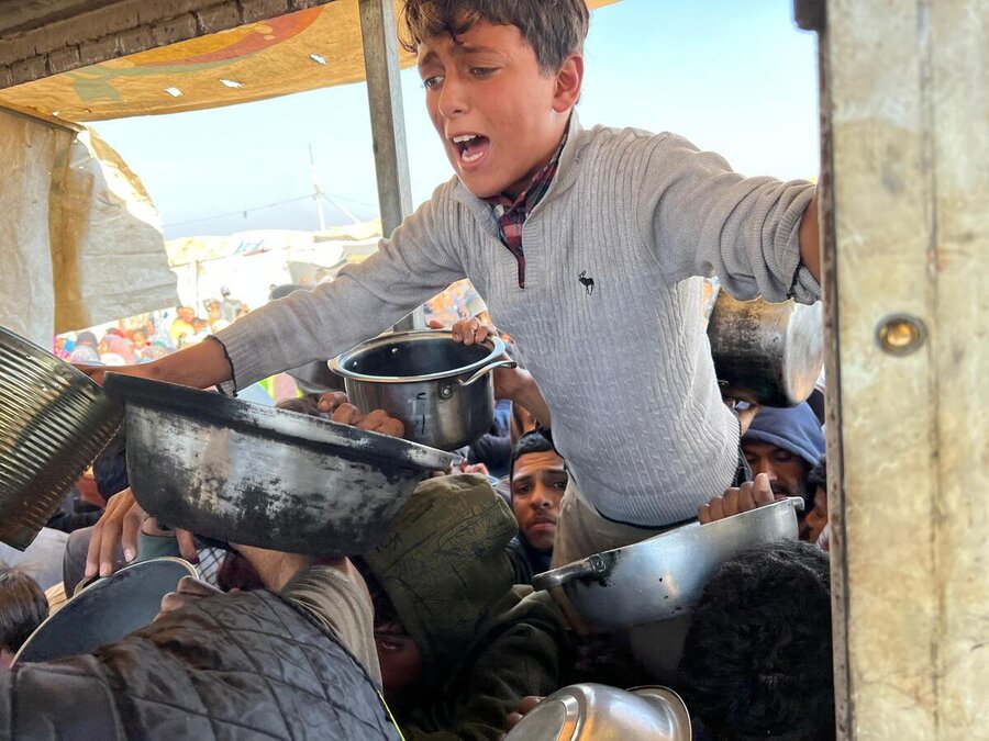 People in Khan Younis, Gaza, thrusting out bowls for food. Photo: WFP/Jonathan Dumont