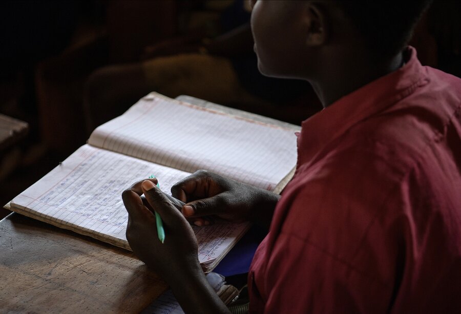 A closeup of a young student writing in his notebook. Photo: WFP/Alessandro Abbonizio