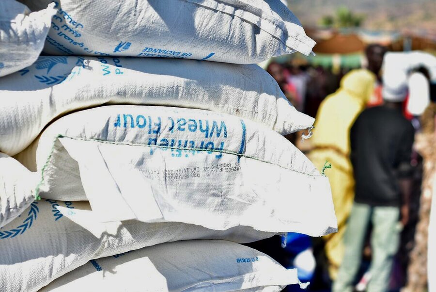 A pile of WFP food bags , backdropped by images of people. Photo: WFP/Mohamed Hanay