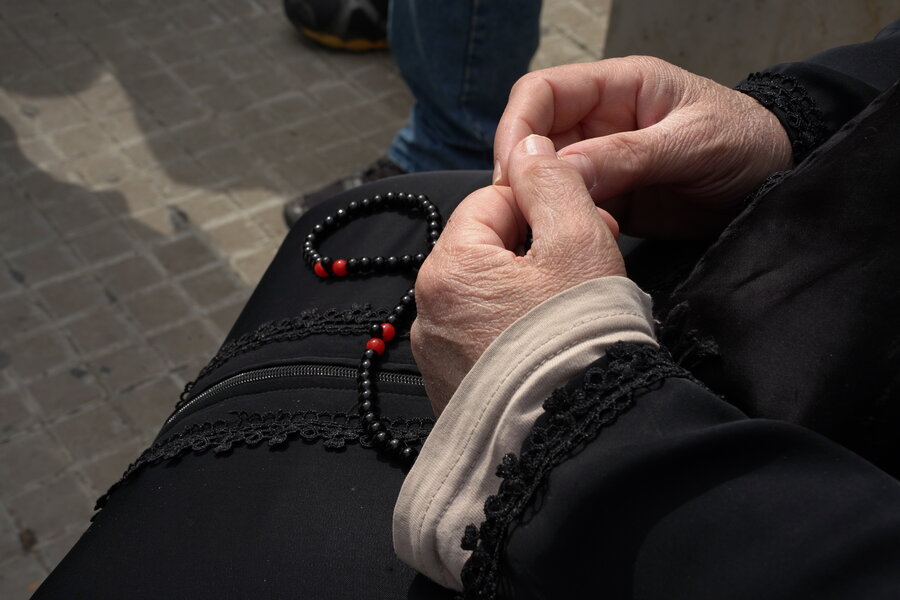 A closeup shot of a woman's hands classing dark prayer beads. Photo: WFP/Khadija Dia 