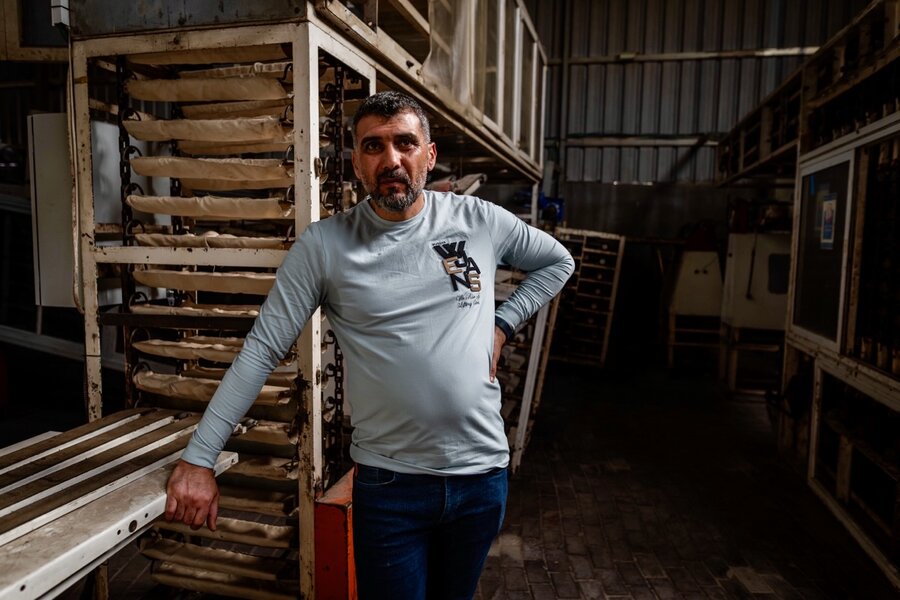 A man stands in front of a large - and empty - bakery with bread trays piled behind. Photo: WFP/Maxime Le Lijour