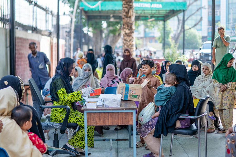Women and children pack a local health clinic in Pakistan, waiting their turn to see a health worker sitting at a table in the middle of the room. Photo: WFP/Pakistan