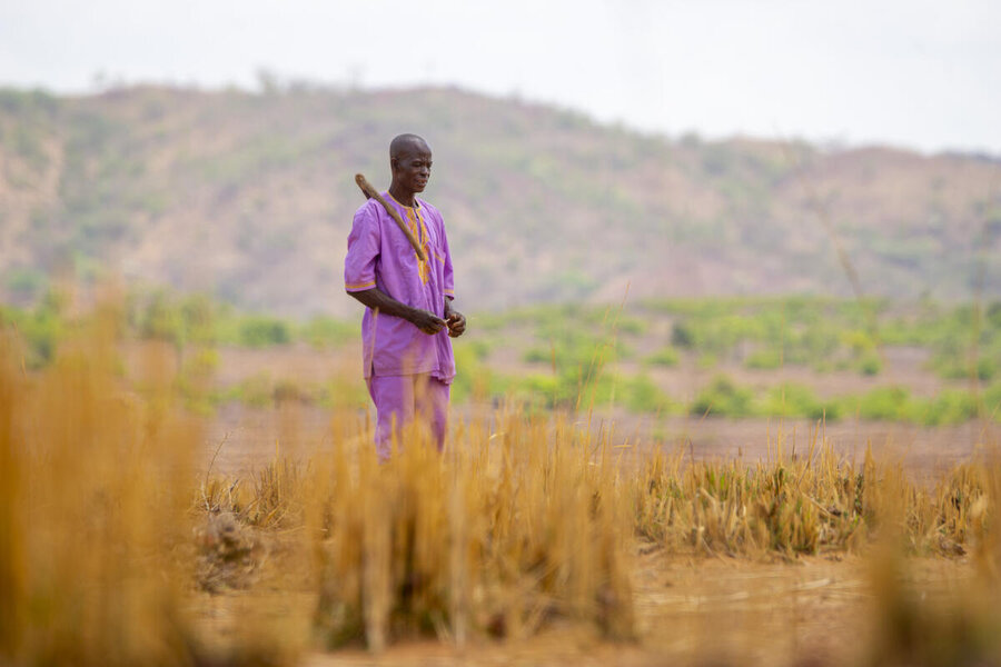 A farmer wearing a purple outfit stands in an arid field in Burkina Faso. Photo: WFP/Cheick Omar Bandaogo