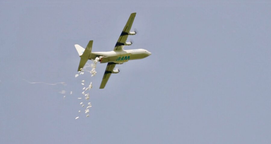 A WFP plane drops white bags of humanitarian assistance backdropped by a blue sky. Photo: WFP/Gabriela Vivacqua
