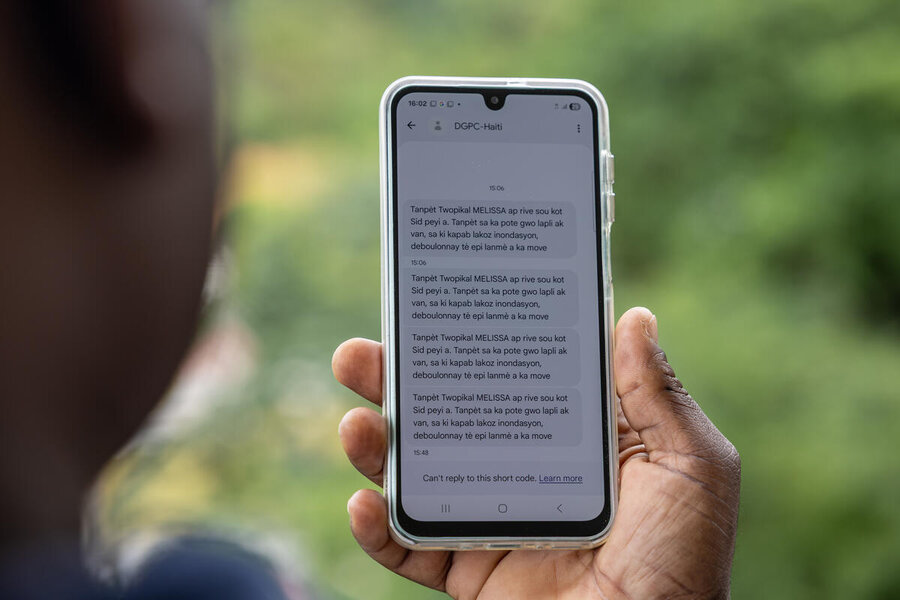 The back of a man's head as he looks at his phone which has an early warning message ahead of Hurricane Melissa. Photo: WFP/Irshad Khan