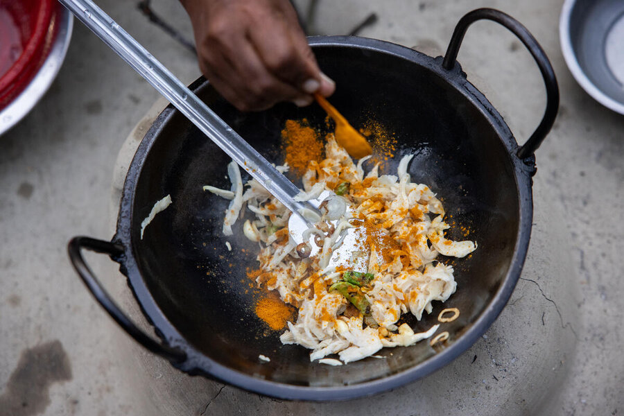 A closeup of a pan of mushrooms frying in a pan and the hand of a woman adding spices. Photo: WFP/Samantha Reinders 