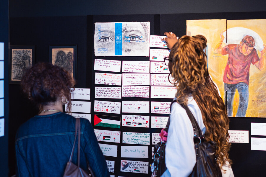 People attending an art exhibit pin notes with their reactions on a wall. Photo: WFP/Axel Brumberg