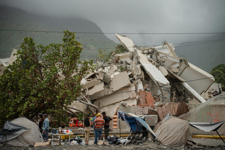 People standing in front of a demolished building and other rubble with mountains in the backdrop.Photo: WFP/Gustavo Vera
