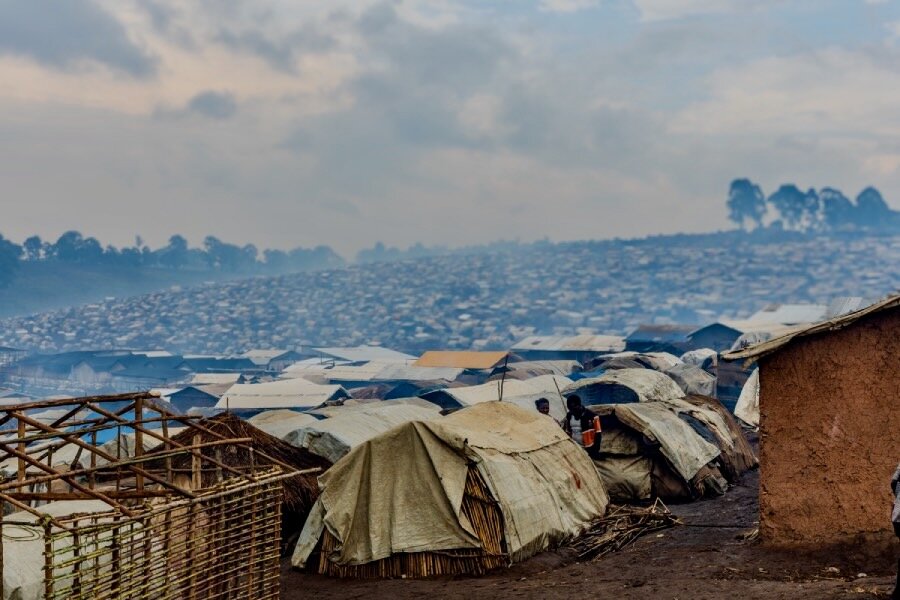 A wide shot of a displacement camp, packed with white tents, under cloudy skies. Photo: WFP/Charly Kasareka