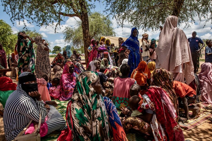 A crowd of women in long, colorful robes, await nutrition treatment at South Sudan's Wedweil Refugee Settlement. Photo: WFP/Gabriela Vivacqua