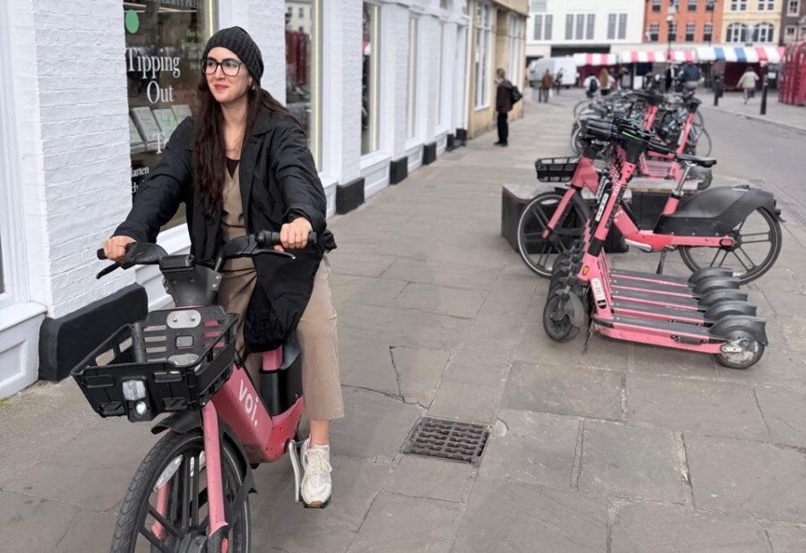 A woman in a black cap and coat on a pink bike. Photo: Courtesy of Noor Al Khouri
