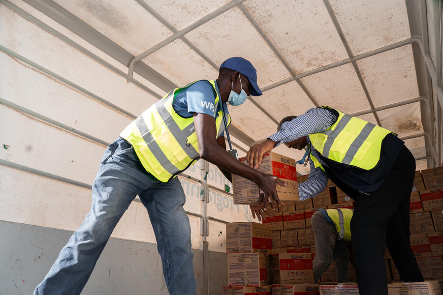 WFP staff unload boxes of nutrition supplies from a truck during an operation.