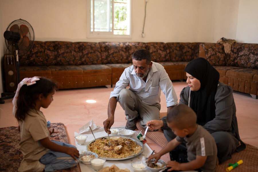 A West Bank family gathers inside around a large plate of food on the floor, sharing it in traditional style. Photo: WFP/Hugh Rutherford