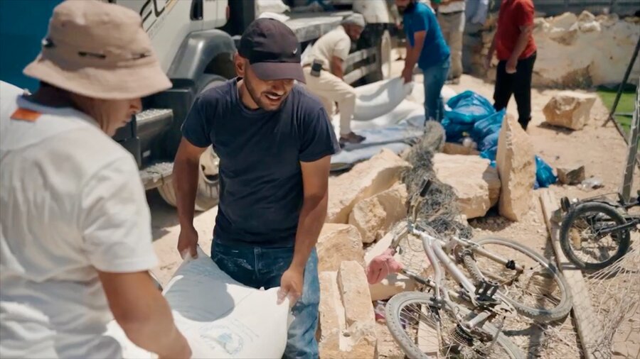 Man carry bags of WFP food assistance in the West Bank. Photo: WFP/Hugh Rutherford