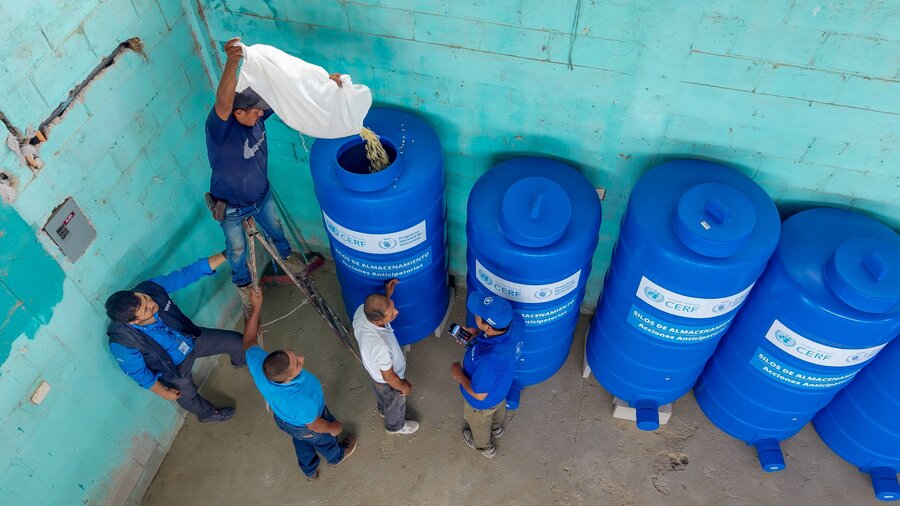 Men pour grains into large blue plastic community silos in Guatemala's Dry Corridor.  The stored food will tide local communities by during the El Niño drought. Photo: WFPTVN Producciones