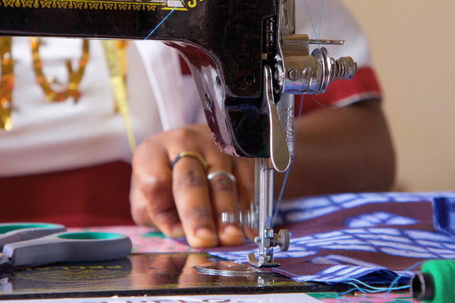 A closeup of a hand guiding cloth through a sewing machine. Photo: WFP/Nhetem Incute
