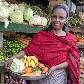 Woman smiling and holding a bowl of fruit and vegetables