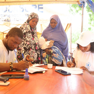 Two women benefiting from WFP food and nutritional assistance register at a distribution site in Malanville.