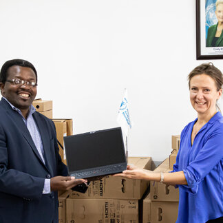 A man and a woman are holding a laptop together
