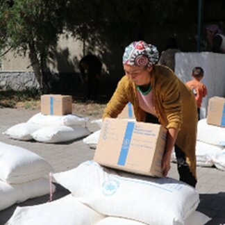 A women lifts a WFP box of food assistance. Photo: WFP