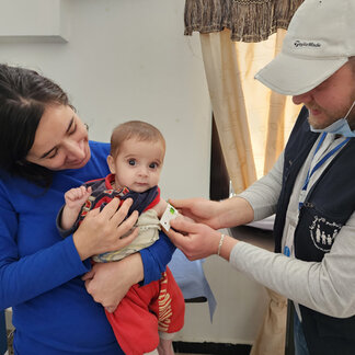A health worker measures the mid-upper arm circumference (MUAC) of a baby girl at a WFP-supported Community-based Management of Acute Malnutrition (CMAM) clinic in Tartous to assess her nutritional status. Photo: WFP/Sana Saddakni