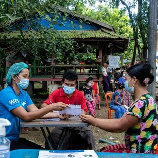 WFP staff giving cash assistance to people affected by conflict and disasters.