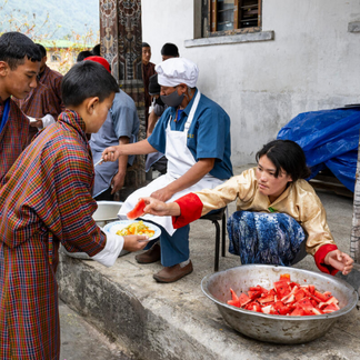 Person tending mushroom-growing bags inside a rustic production space, supporting resilient food production and local livelihoods.