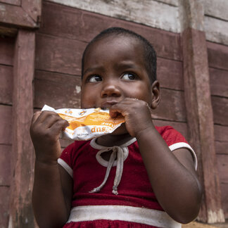 A child is holding a snack, distributed by WFP, in his hands.
