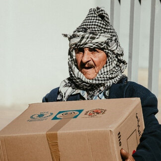 A man holds a box of food assistance, a tangible representation of the Japanese contribution, during a food distribution initiative facilitated by WFP - 2022 / PHOTO: Ikigai Photo Company   