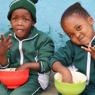 Happy learners eating lunch meal of staple pap and split green peas