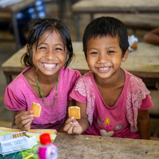 two kids at school holding a biscuit 