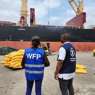Two WFP staffers stood on shore looking at a boat