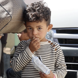 A young boy in Syria eating a WFP date bar