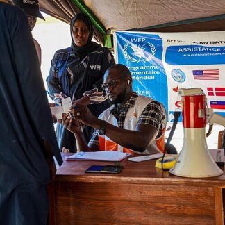 WFP staff register displaced people at an assistance site, checking documents and coordinating relief operations in Chad.