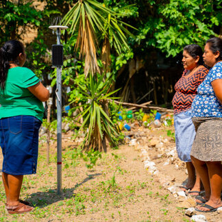 Gloría Díaz de Maldonado, WFP programme participant, shares climate information with other beneficiaries working in the local garden.