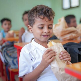 Boy eating a food roll in classroom