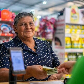 Woman handing over cash at shop till