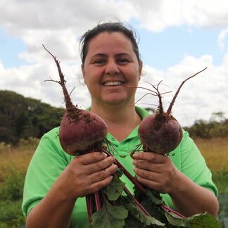A woman standing and holding raw beetroot.