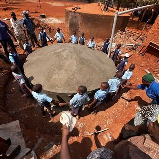 Children surrounding a water cistern.